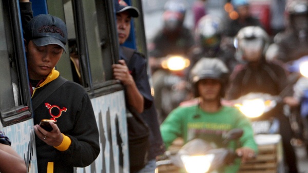 Menino na porta do ônibus olhando seu smartphone 