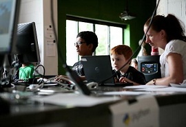 Professora ensinando duas crianças a mexerem no computador